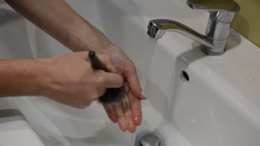 Kadınlar makyaj fırçalarını musluk suyuyla yıkıyor.