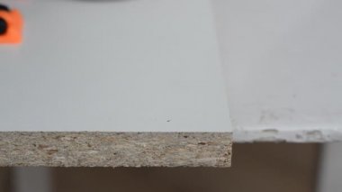 Usta onaylayıcı bir vida için tahta bir levhada delik açıyor.