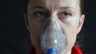 Kadın, arka planda nefes alırken maskenin içine nefes alıyor.