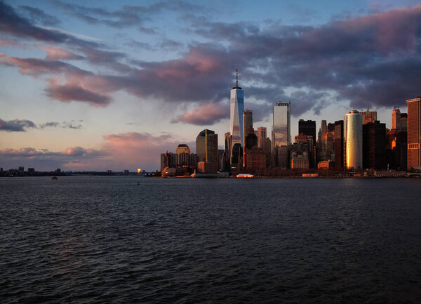 New York City skyline with urban skyscrapers over Hudson River at sunset. Manhattan downtown panorama. Waterfront view to the harbor at twilight.