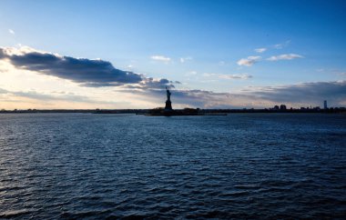 Hudson Nehri manzaralı özgürlük heykeli mavi gökyüzü ve gün batımında sonsuz ufuk karşı silüeti. New York City ikonik turistik.