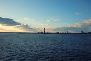 Hudson Nehri manzaralı özgürlük heykeli mavi gökyüzü ve gün batımında sonsuz ufuk karşı silüeti. New York City ikonik turistik.