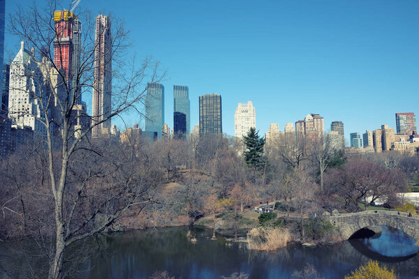 New York City skyline with urban skyscrapers. Spring view of the lake and a bridge in Central park.
