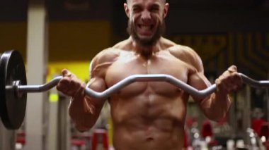 Atletik adam bir halter ile pazı için bir egzersiz yapar.