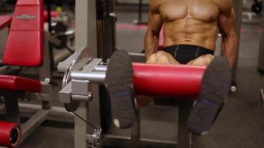 Atletik adam simülatörde bir uzatma bacak egzersiz gerçekleştirir