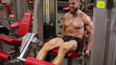 Atletik adam simülatörde bir uzatma bacak egzersiz gerçekleştirir