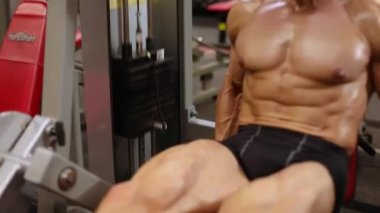 Atletik adam simülatörde bir uzatma bacak egzersiz gerçekleştirir