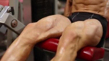 Atletik adam simülatörde bir uzatma bacak egzersiz gerçekleştirir