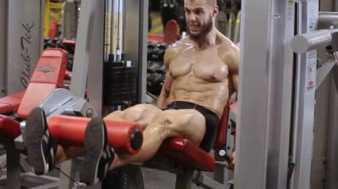 Atletik adam simülatörde bir uzatma bacak egzersiz gerçekleştirir