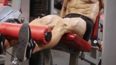 Atletik adam simülatörde bir uzatma bacak egzersiz gerçekleştirir