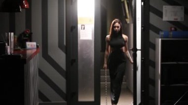 Atletik kız elinde zincirler ile spor salonuna gider.