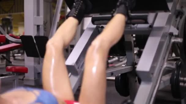 运动女孩在模拟器中执行腿部压榨练习 — 图库视频影像