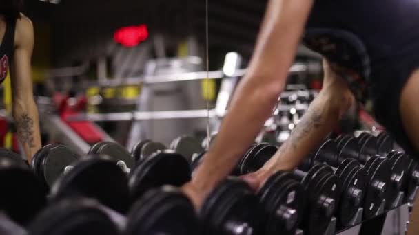 Athletisches Mädchen Nimmt Und Legt Hanteln Einer Hantelreihe Zurück — Stockvideo