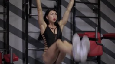 Atletik kız asmak bacaklar yükselterek bir dizi gerçekleştirir ve bar yukarı çekerek
