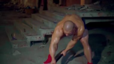 Atletik adam lastiğe çekiç darbesi uyguluyor.