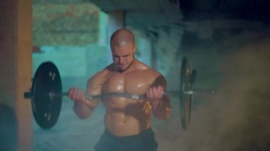 Atletik adam terkedilmiş bir binada pazı egzersizi yapıyor.