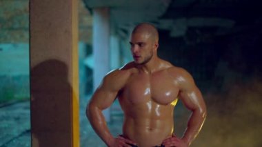 Çıplak gövdeli atletik bir adam tatbikattan sonra yıkılmış bir binada duruyor.