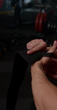 Adam spor salonunda bileğini bandajla sararak ağırlık kaldırmaya hazırlanıyor. Bu uygulama destek arttırır ve çalışmalar sırasında yaralanma risklerini en aza indirir.