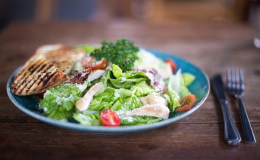 Mavi plaka ile cuttlery bir kenara koyu ahşap masa üzerinde taze Sezar salata