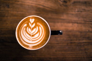 Ahşap sıcak cappucino bardak geçerli. Bir sanat latte üzerinde.