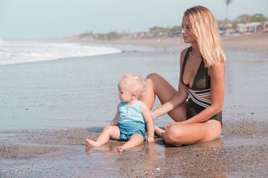 Genç bin yıllık anne onun şirin bebek çocuk sahilde ile zaman harcamaktadır. Mutlu aile, birlikte oynama. Eğlence etkinlik kavramı.