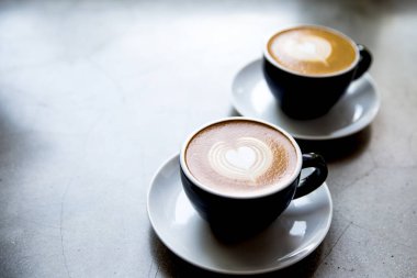 İki siyah aşk sanat latte ile lezzetli cappucino bardak.