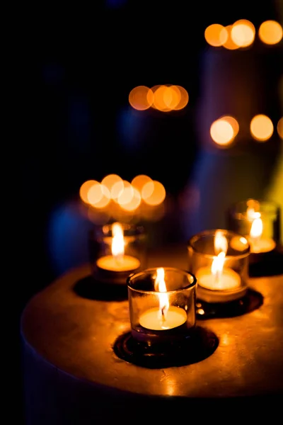 Chama de muitas velas queimando em luzes embaçadas fundo . — Fotografia de Stock