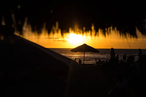 Techo de playa de paja en el café con gente borrosa en el hermoso atardecer tropical . — Foto de Stock