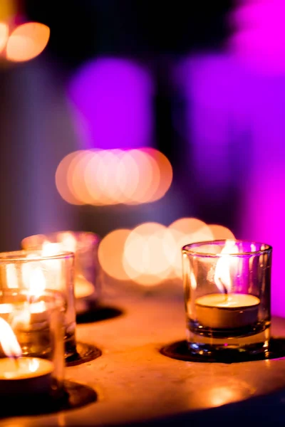 Płomień wielu świec płonących na fioletowym niewyraźne tło. — Zdjęcie stockowe