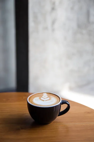 Sabroso capuchino con hermoso arte latte en la mesa de madera en el café . — Foto de Stock