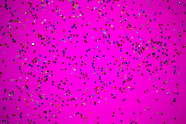 Multicolored stars glitter on brigth pink neon background.