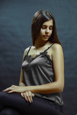 Gri ipek bluzlu, uzun saçlı, güzel, esmer bir kadının bel portresi..