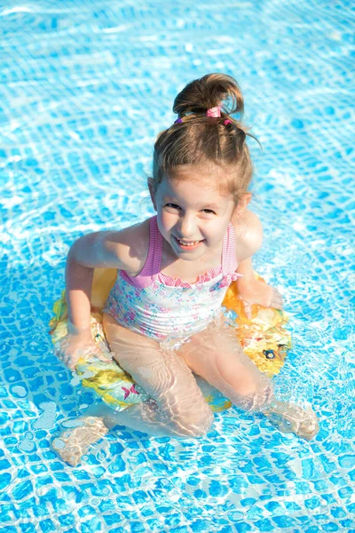 Engraçado menina nada na piscina em um lifebuoy amarelo — Fotografia de Stock