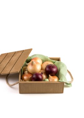 Kırsal ahşap bir kutuda, sarı ve kırmızı soğanlar beyaz arka planda, yan görünüşte izole edilmiş..