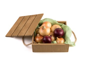 Sarı ve kırmızı soğanlar, beyaz bir arka planda yeşil keten peçetede, tahta bir kutunun içinde..