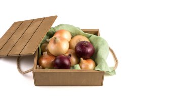 Kırsal ahşap bir kutuda, sarı ve kırmızı soğanlar beyaz arka planda, yan görünüşte izole edilmiş..