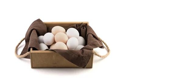 Jaja kurze są białe i brązowe w pięknym drewnianym opakowaniu z brązową serwetką lnianą. — Zdjęcie stockowe