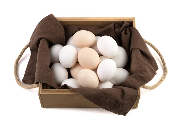 Os ovos de galinha são brancos e marrons em um belo pacote de madeira com um guardanapo de linho marrom. — Fotografia de Stock