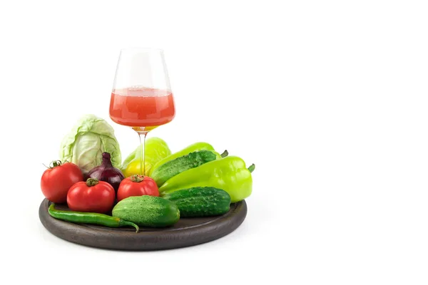 Ein Glas frisch gepresster Gemüsesaft und frisches Gemüse auf einem runden Tablett auf weißem Hintergrund. — Stockfoto