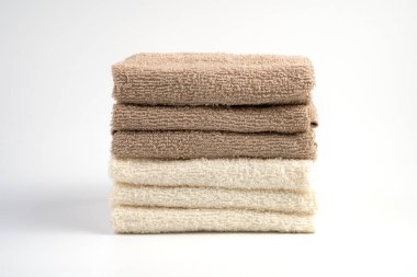 Beyaz arka planda beyaz ve açık kahverengi Terry havluları yığını.