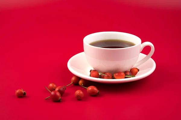 Здоровый чай шиповник в красивой белой чашке на красном фоне. — стоковое фото
