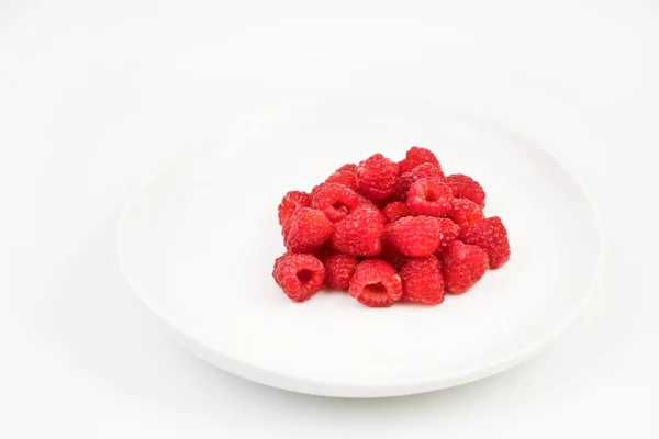 Frambuesas en un plato blanco sobre un fondo claro. Fondo de la baya. —  Fotos de Stock