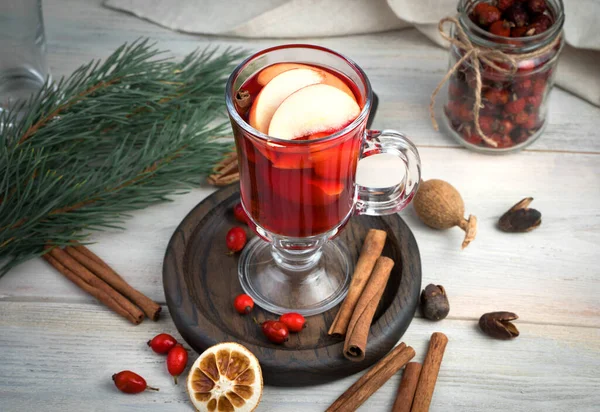 Hot Christmas mulled wine on a background of festive attributes, cinnamon and lemon on a light wooden background. — Stock Photo, Image