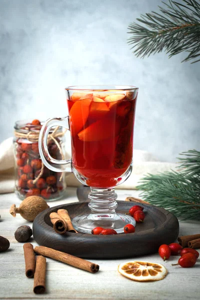 New years drink mulled wine surrounded by spices, pine branches, cinnamon sticks, red berries and dried lemons on a wooden background.