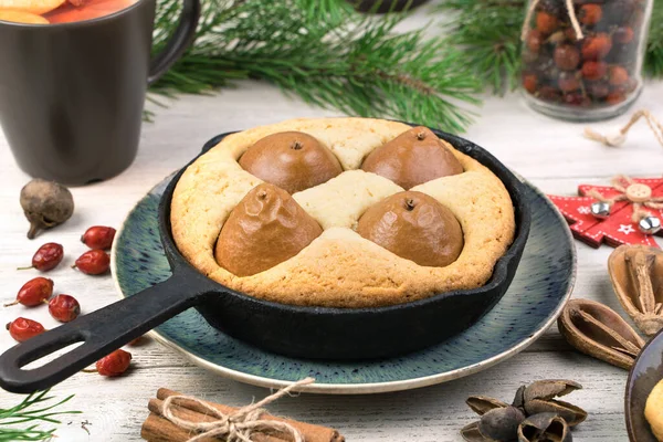 A shortbread pie with shaped fruit on a plate next to a hot drink, cinnamon and pine branches. — Stock Photo, Image