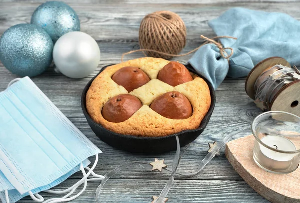 Christmas table with protective masks, cake, and Christmas decorations on a wooden background. — Stock Photo, Image