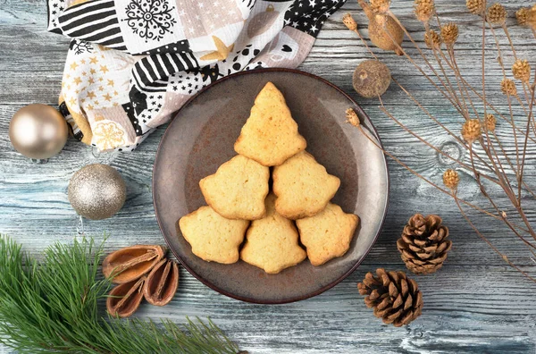 Cookies in the shape of a Christmas tree on a brown plate surrounded by cones and branches. — Stock Photo, Image