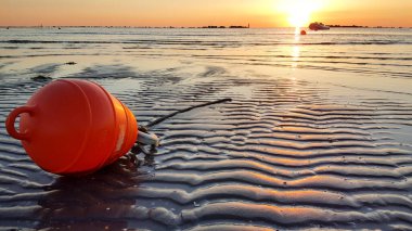 Akdeniz sahilinde gün doğumu, riccione rimini 'de, kumları ve turuncu deniz boasını yansıtan dalgalarla.