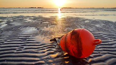 Akdeniz sahilinde gün doğumu, riccione rimini 'de, kumları ve turuncu deniz boasını yansıtan dalgalarla.