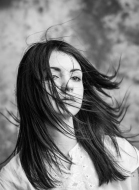 Rüzgarda savrulan uzun saçlı güzel siyah saçlı kızın portresi. Güzel, koyu saçlı, uzun saçlı, rüzgarda uçuşan bir kızın kaliteli portresi.